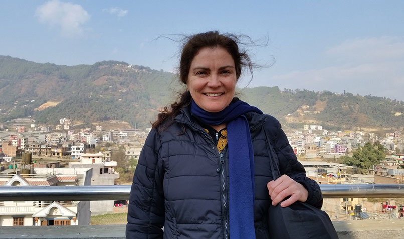 AFID volunteer in front of scenic mountain backdrop in Nepal